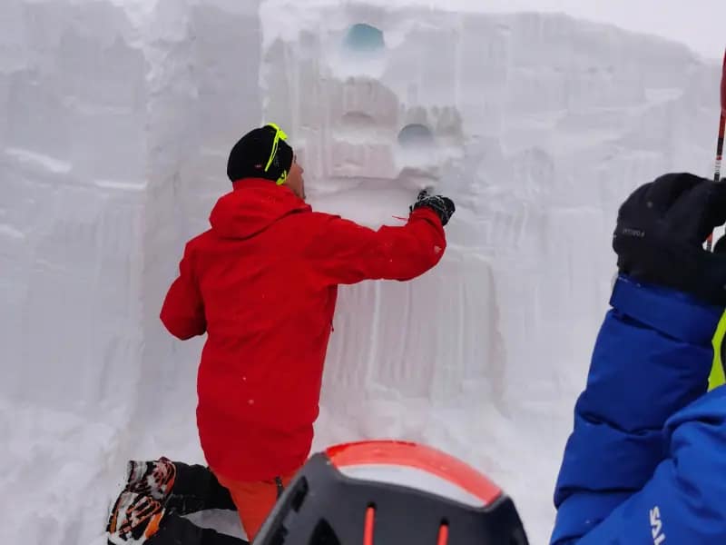 Téli magashegyi tanfolyam - 3 nap az Alpokban MountainGo módra 20 Hegyi túravezető hóprofil elemezést mutat be egy hófal előtt a téli magashegy tanfolyamon